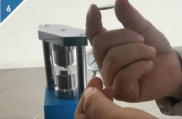 6. Estrarre la batteria a bottone sigillata dalla sigillatrice.